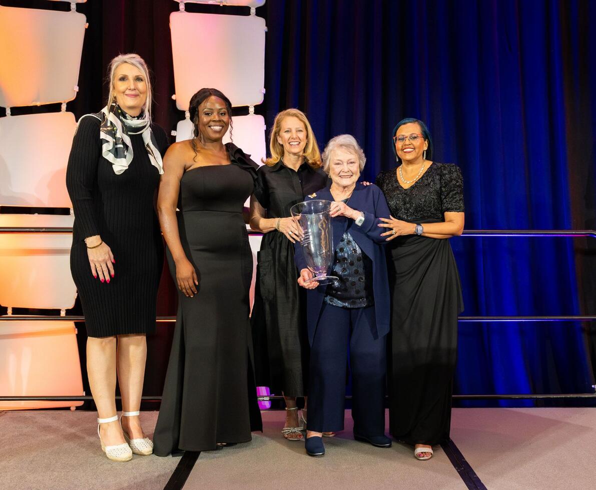 A group of professional women receiving an award on a stage