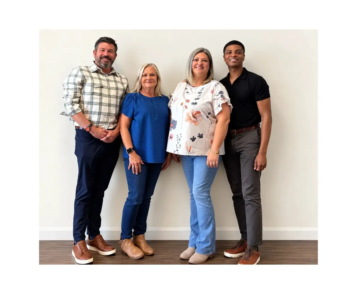 A group of 4 professionals smiling and standing in front of a blank background