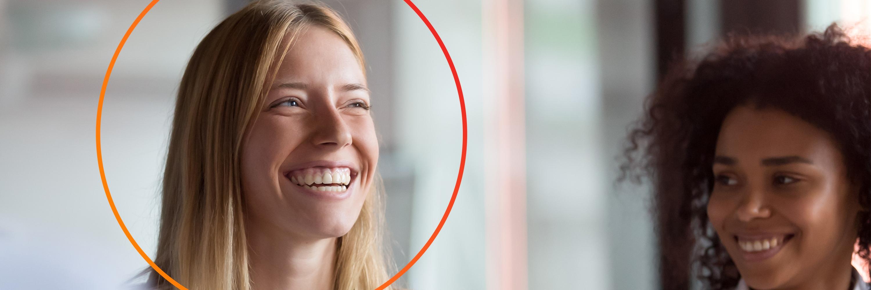 Two women smiling, blond woman has orange circle around head