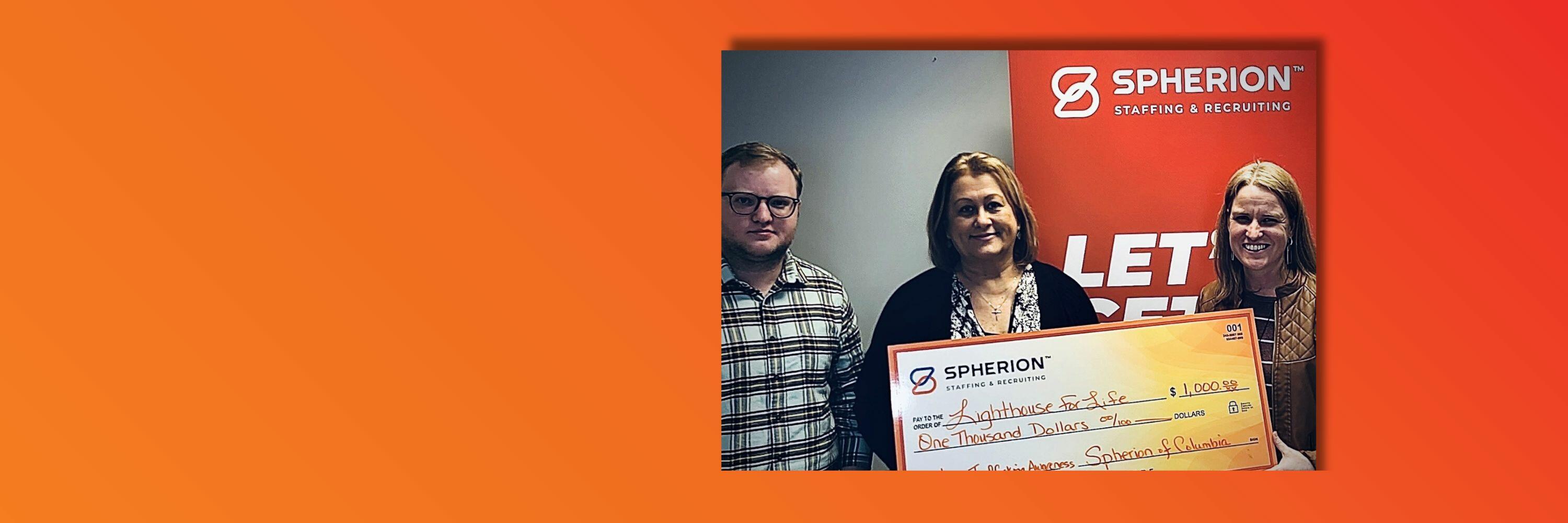 Orange background with photo of three people smiling and holding a giant check