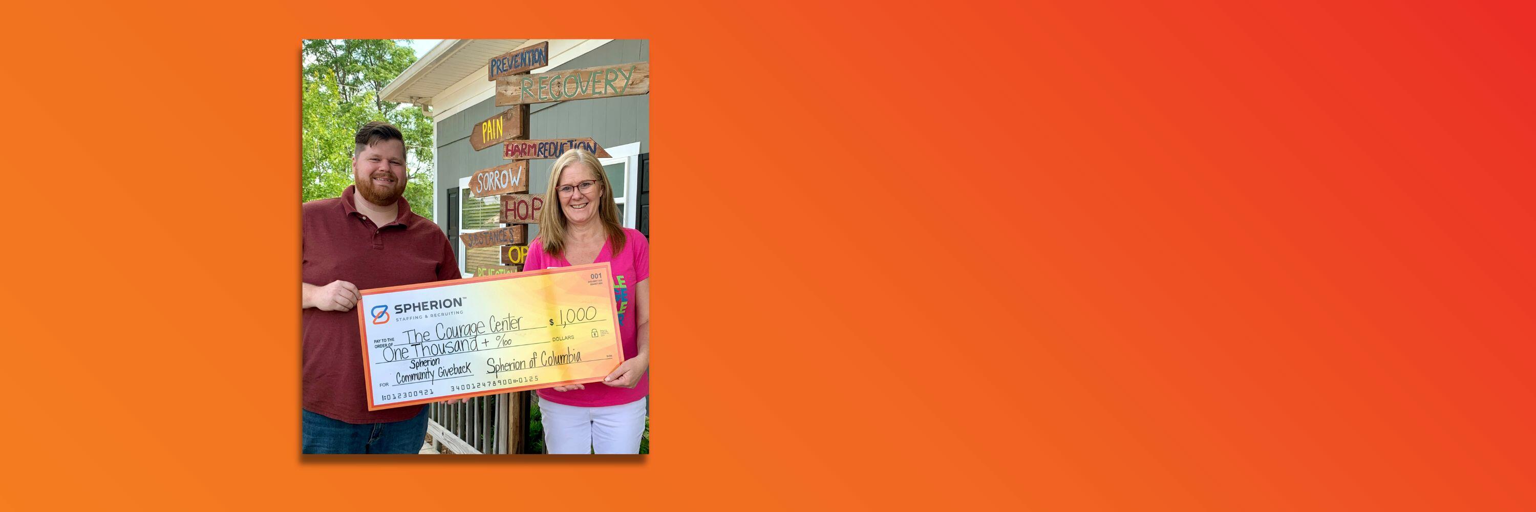 Orange background with a photo of a man and woman smiling and holding a giant check