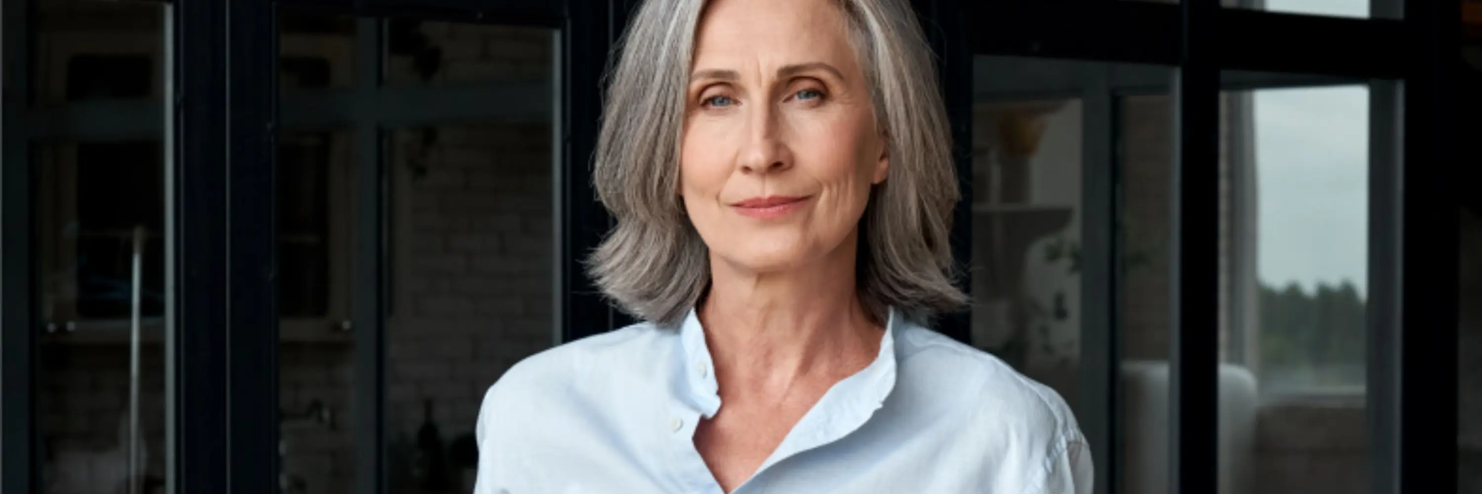 Mature female executive in a light blue blouse in a dark office
