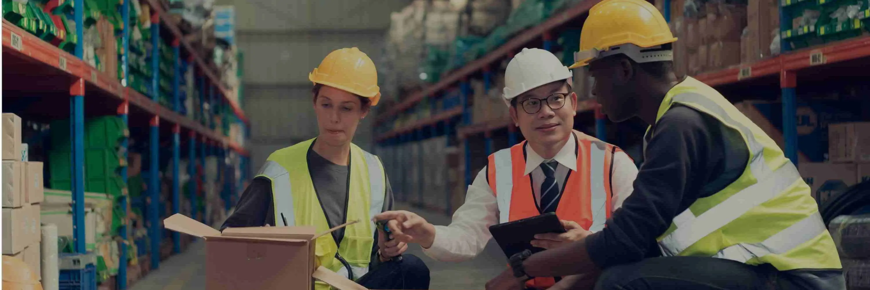 Three employees in hard hats in a warehouse setting