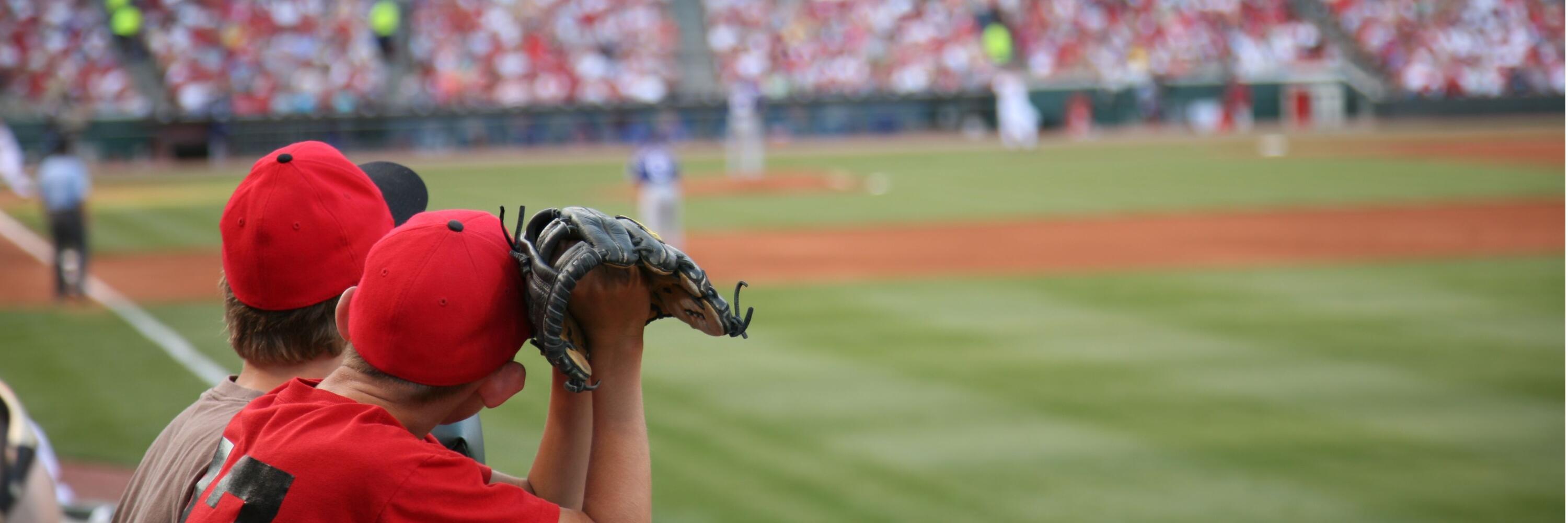 Two boys holding baseball gloves looking at a baseball field