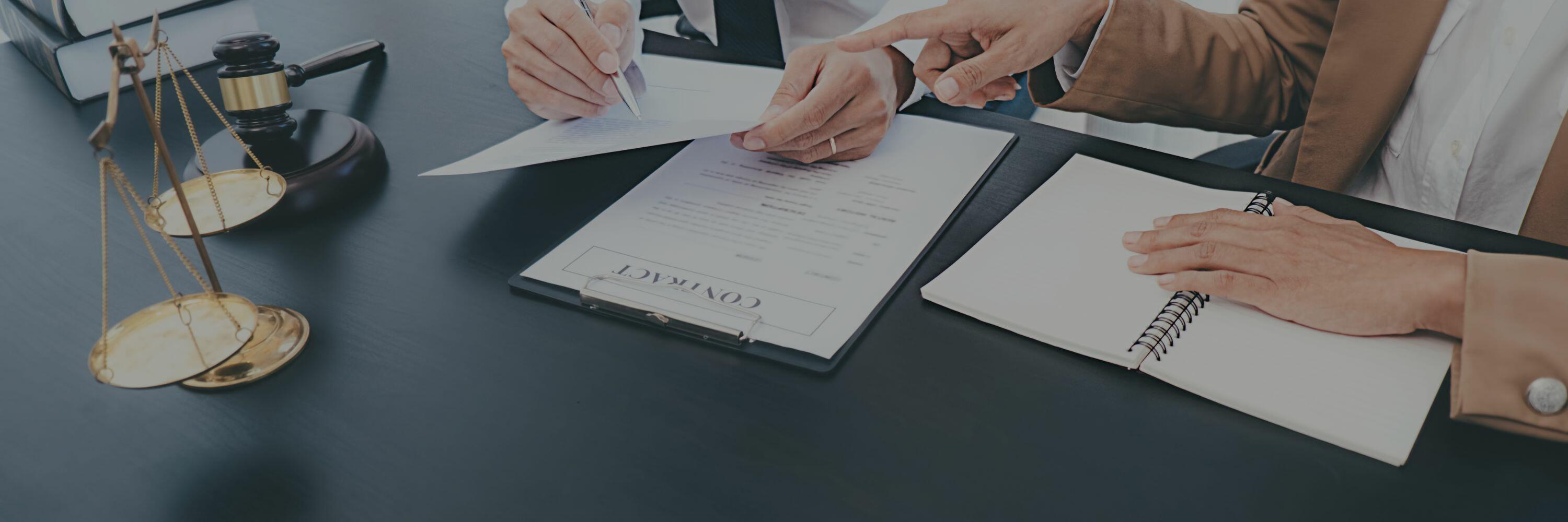 A photo of two people sitting at a legal desk reviewing a contract