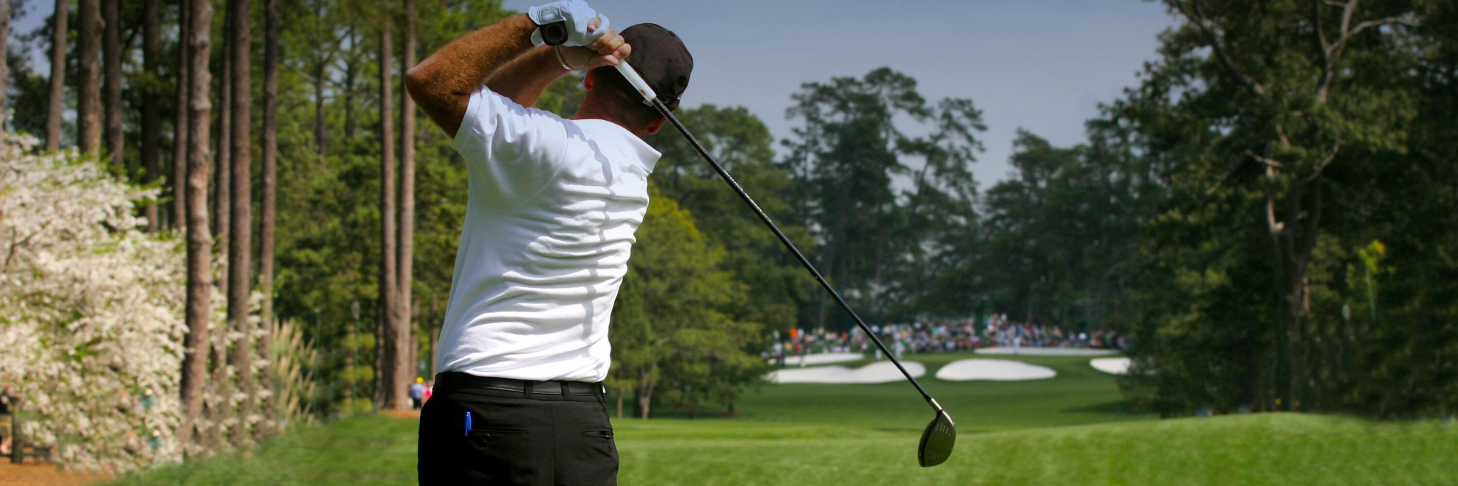 Photo of a golfer swinging his golf club on a green golf course