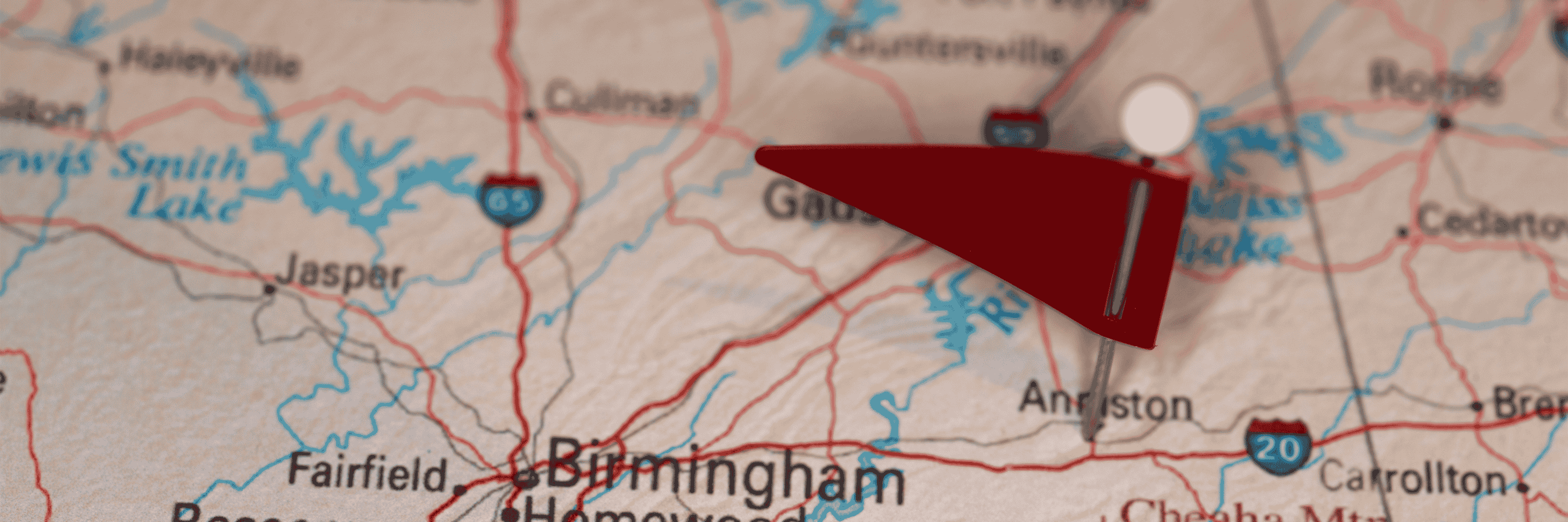 Picture of a map of Alabama with a red flag pinned to Anniston