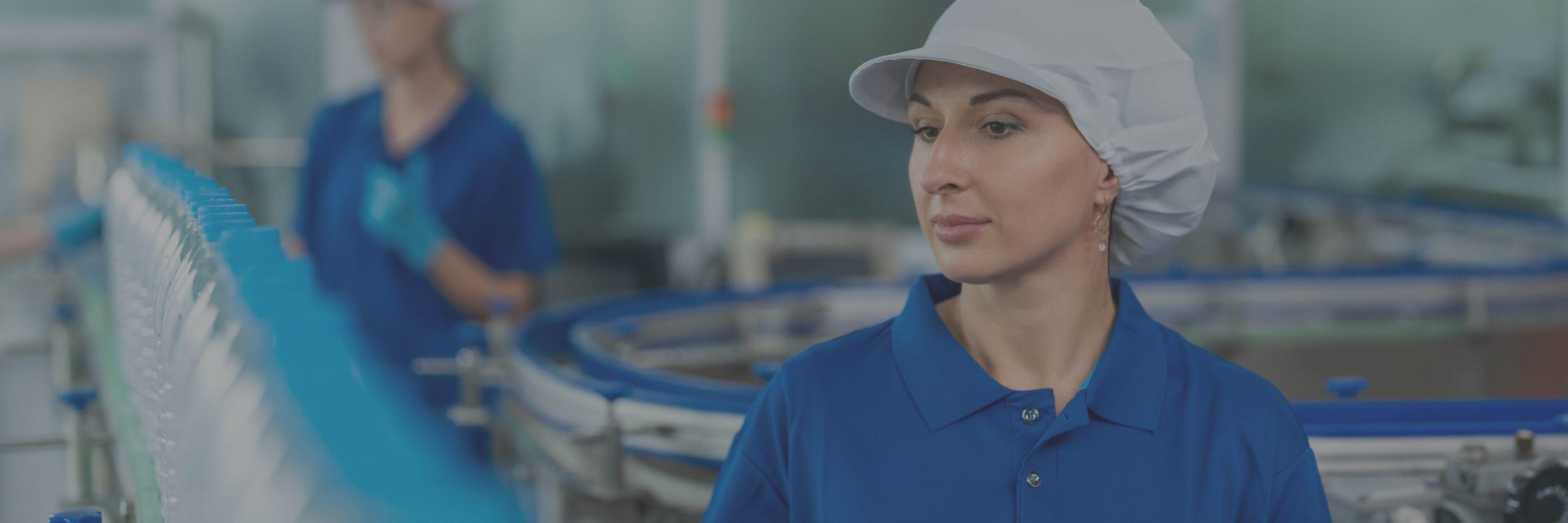 Female food production worker in a blue outfit and white hat