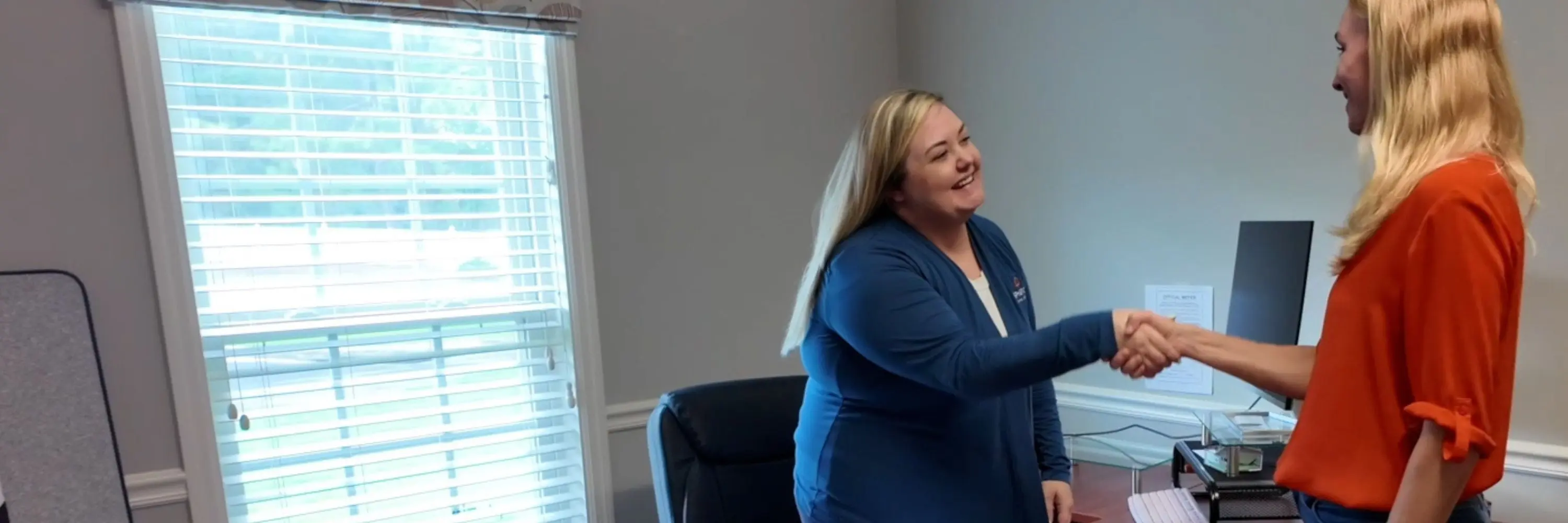 Two women shaking hands in an office