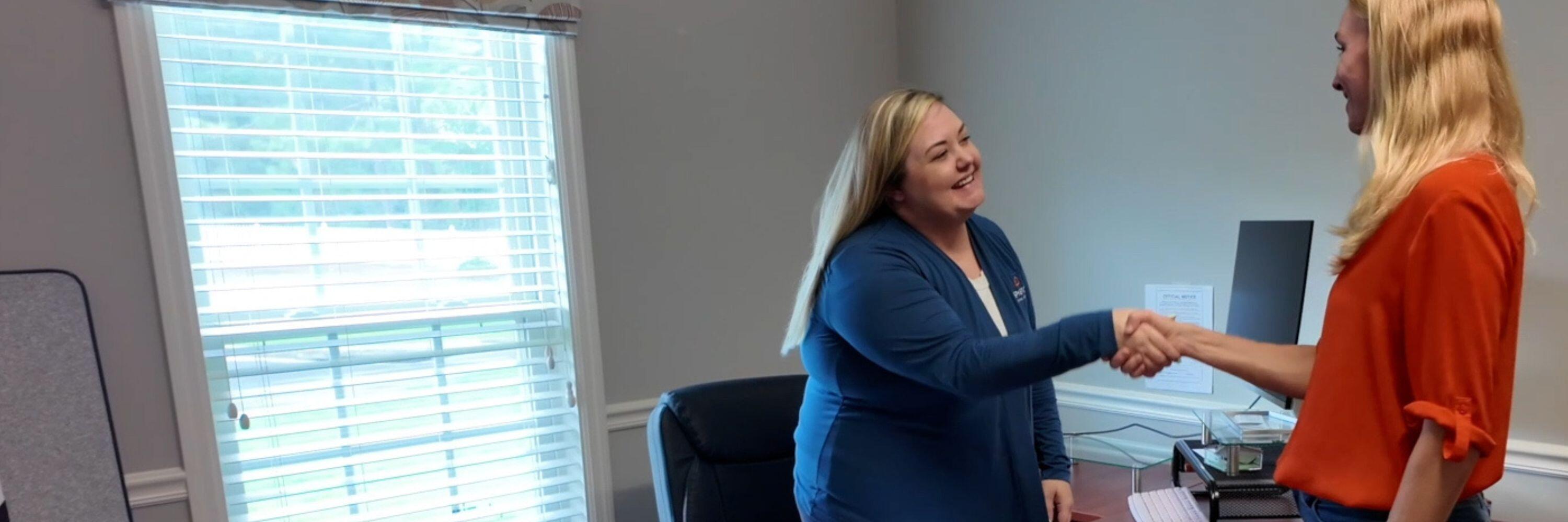 Two women shaking hands in an office