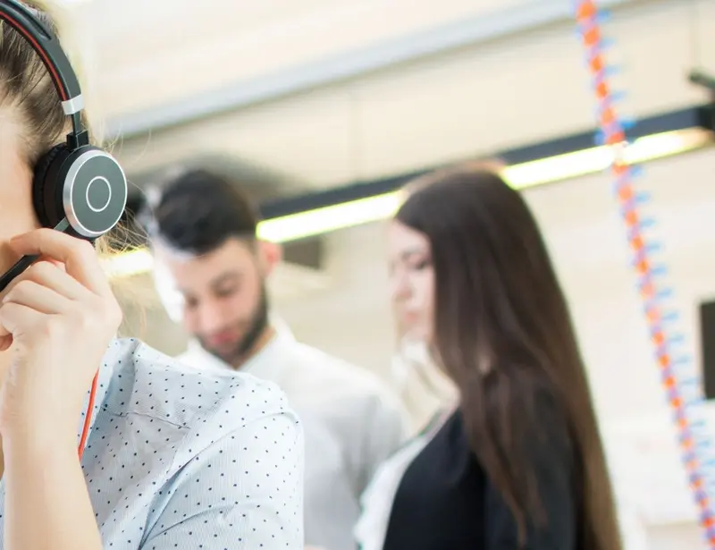 Woman looking at a computer wearing a headset and smiling