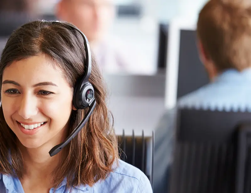 Woman looking at a computer wearing a headset and smiling