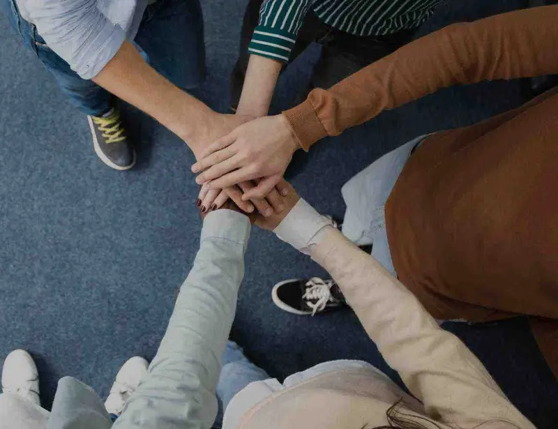 Aerial view of people forming a hub-and-spoke formation with their hands