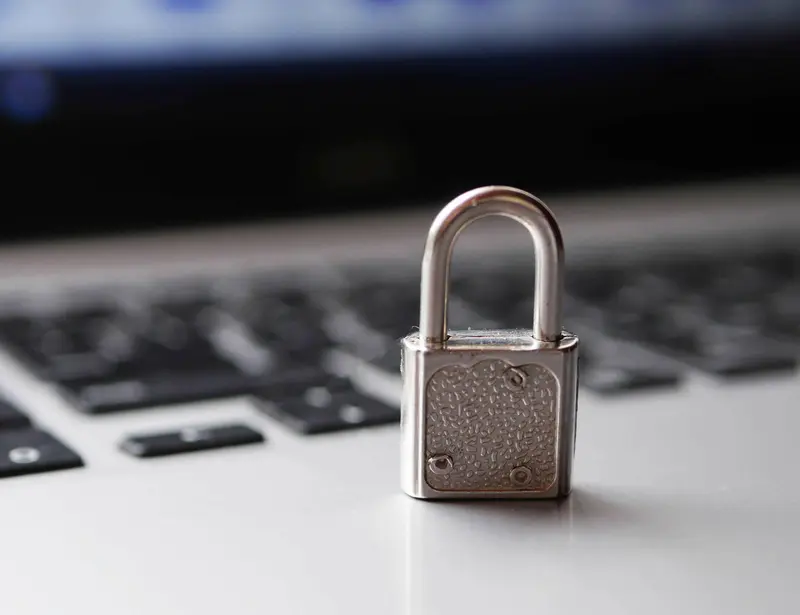 Blurry close-up image of a laptop with a silver padlock on top of the keyboard