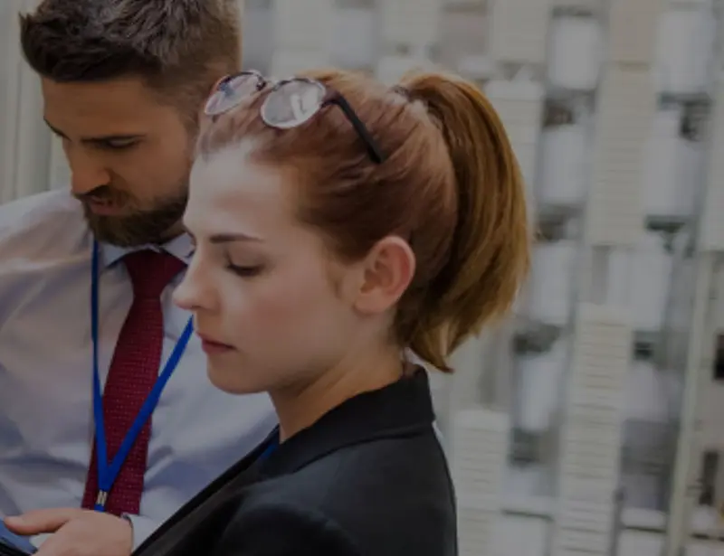 Woman and man working in a server room looking at a laptop