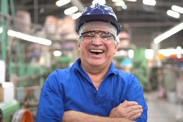 Older man in blue hard hat laughing at the camera