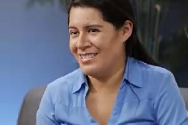 Photo of a woman in a blue button down shirt smiling at the camera
