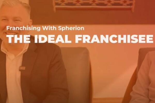 Orange tinted photo of a smiling man with the words Franchising with Spherion, The Ideal Franchisee
