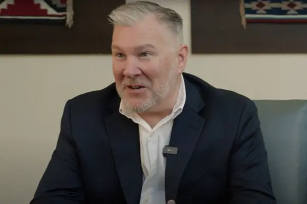 A man smiling and speaking to the side of the camera