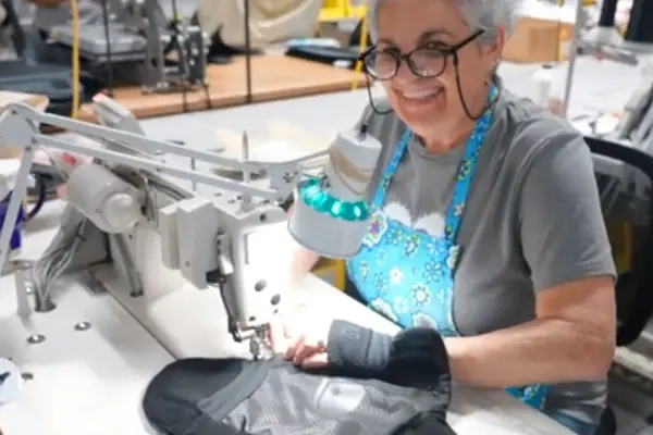 A woman smiling while working at a sewing machine