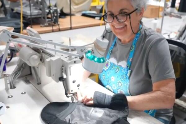 A woman smiling while working at a sewing machine