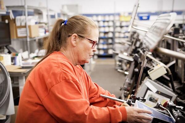 Spherion Staffing is the top staffing agency for manufacturing roles Photo of a woman working in a printing warehouse