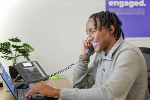 Man talking on the phone while working on a laptop