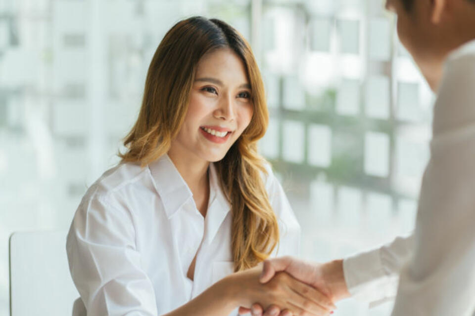 Asian woman shaking hands with a man of camera