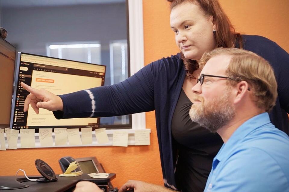 A woman showing a man how to apply on a computer