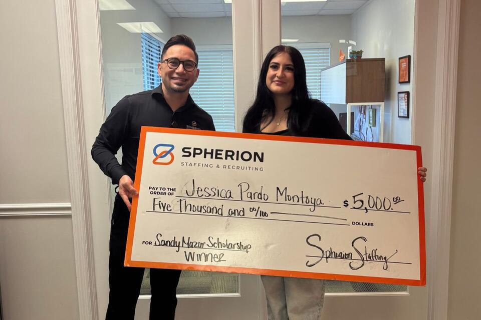 Two people celebrating a scholarship check