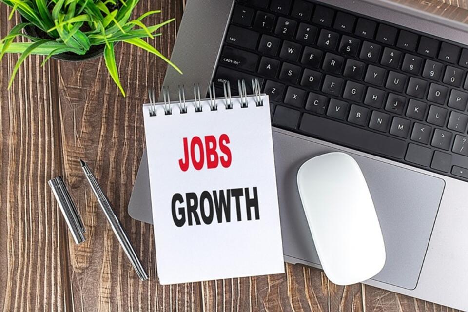 Jobs growth on notepad with laptop keyboard and mouse
