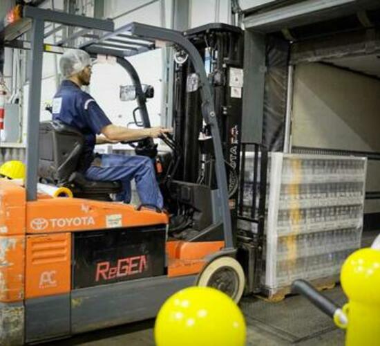 Forklift driver on orange forklift at food production factory