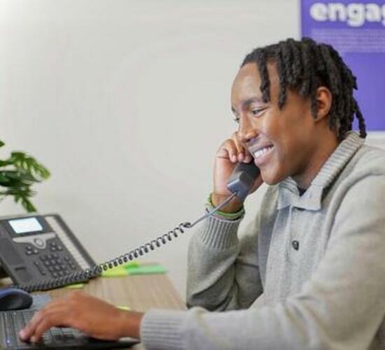 Man talking on the phone while working on a laptop