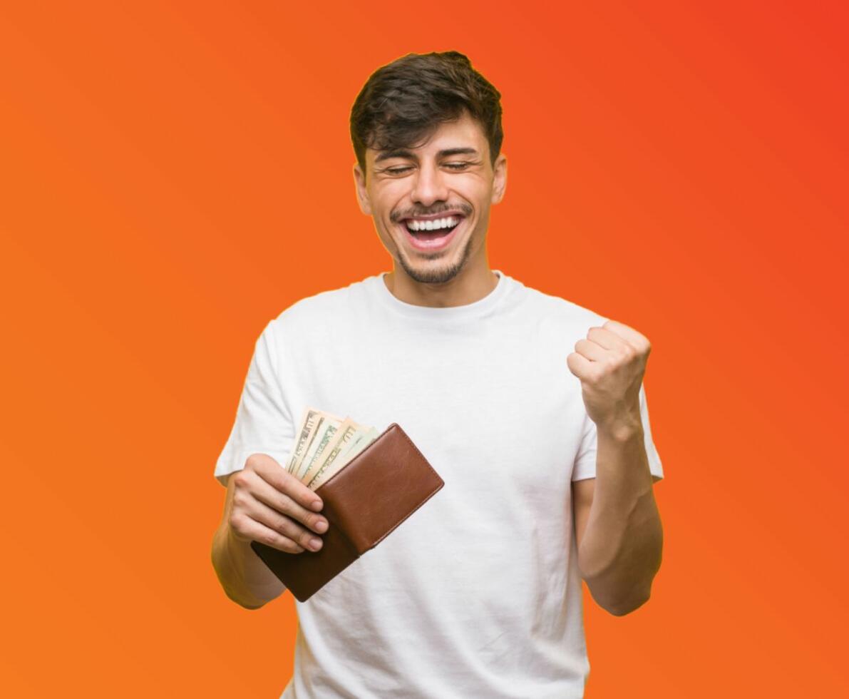 Man in a white shirt smiling and holding a wallet full of cash in one hand and pumping his other hand, on an orange background