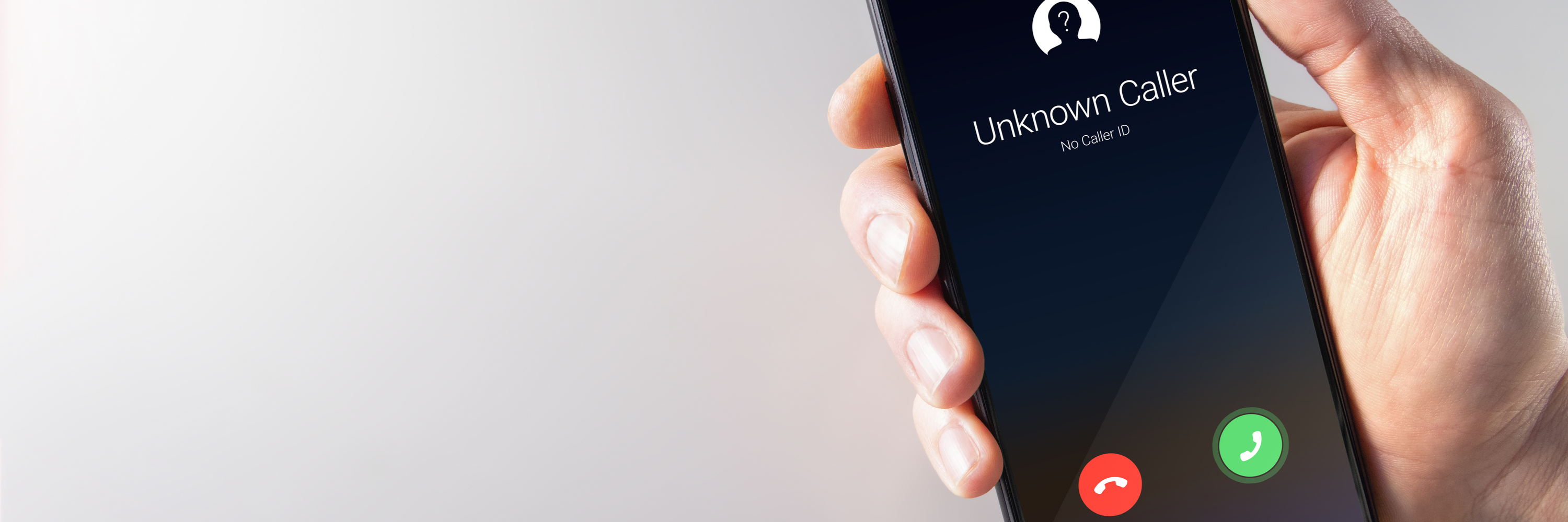 Hand holding a smartphone with unknown caller showing on caller ID